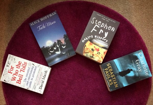 4 books spread out on a purple rug